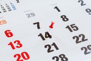 Pin pushed on a calendar concept for an important day.