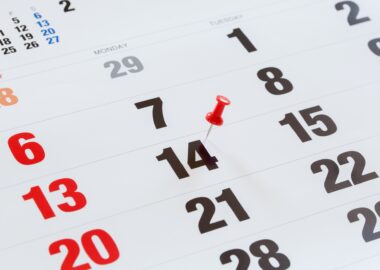 Pin pushed on a calendar concept for an important day.