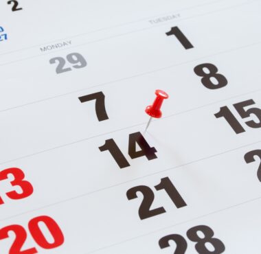 Pin pushed on a calendar concept for an important day.
