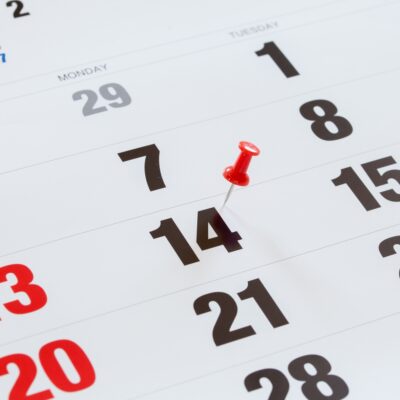 Pin pushed on a calendar concept for an important day.